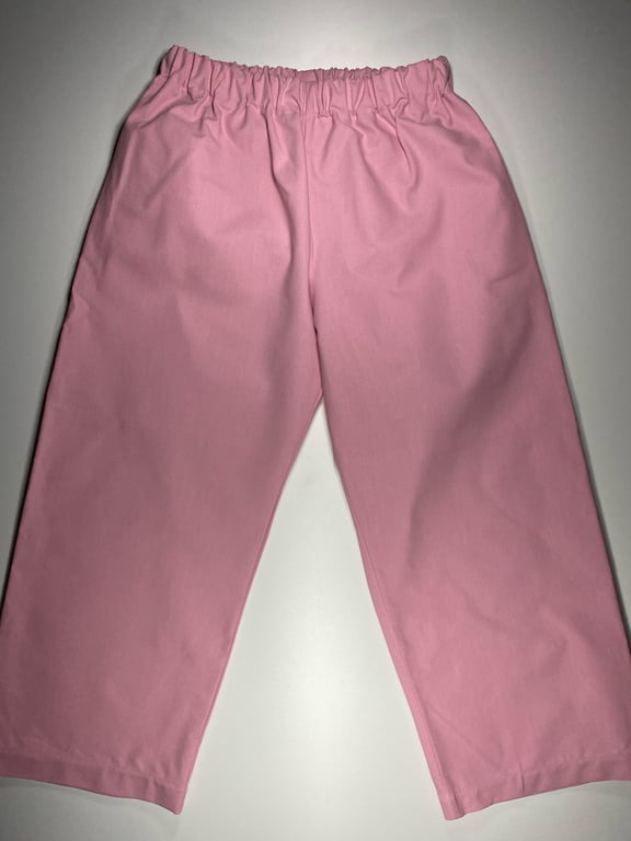 Rosa bukser med elastisk talje lagt fladt på hvidt underlag.