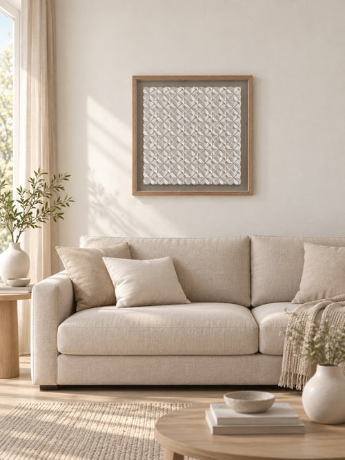 Stue med beige sofa, pude, vægkunst med 3D-mønster, sidebord med vase og planter, samt sofabord med bøger og skål i lyst og naturligt indrettet rum. (2)