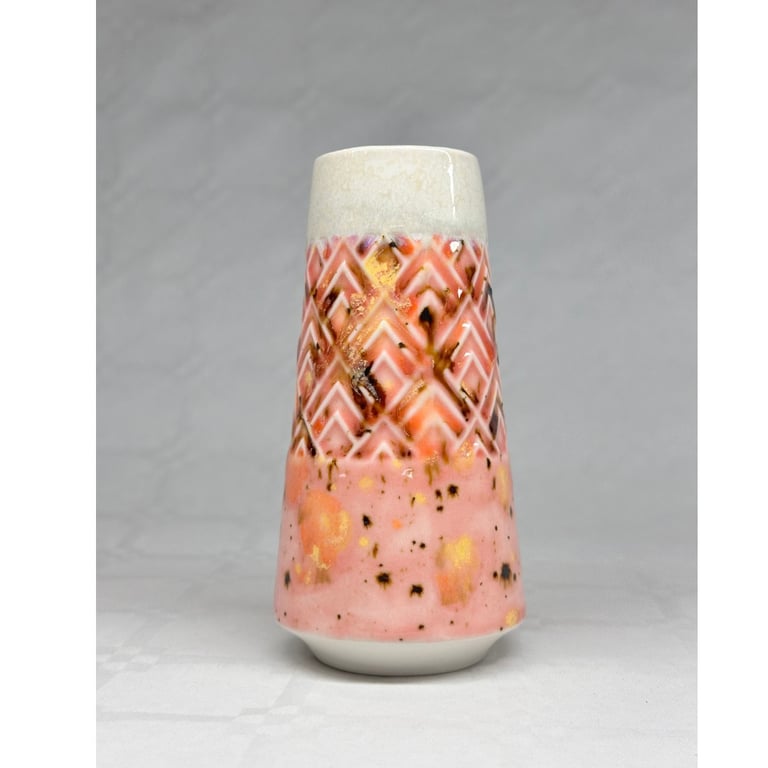 Keramisk vase med rødlig, hvid og brun glasur og geometrisk mønster, placeret på hvid overflade.