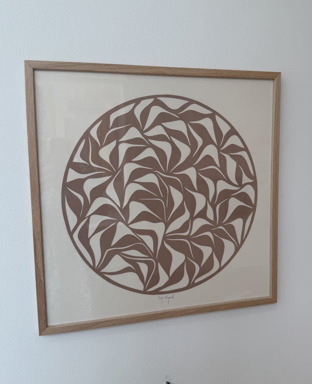Abstrakt vægkunst med brune, urte-lignende former arrangeret i en cirkelramme på beige baggrund.