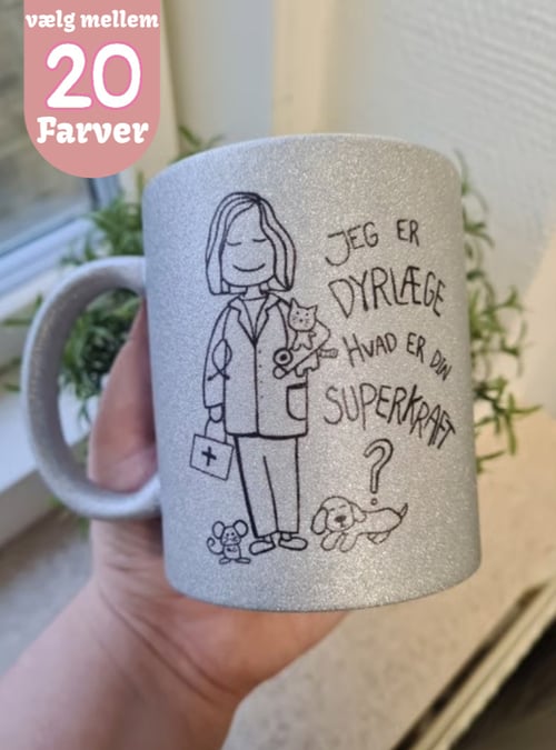 En hånd holder en glitrende kop med en tegning af en dyrlæge, et dyr og teksten: "Jeg er dyrlæge, hvad er din superkraft?". Et lille mærke i øverste venstre hjørne siger "vælg mellem 20 farver". (1)