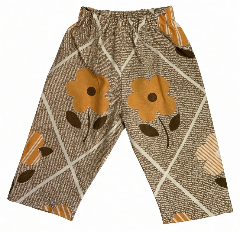 Børnebukser med elastisk talje og blomsterprint i brun og orange farve.