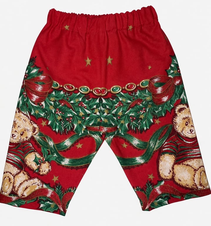 Røde shorts med julemønster bestående af bamser, grønne grene, bånd og guldstjerner.