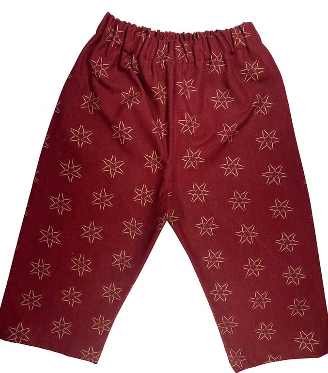 Bordeauxrøde bukser med elastik i taljen og mønster af beige stjerner over hele stoffet.