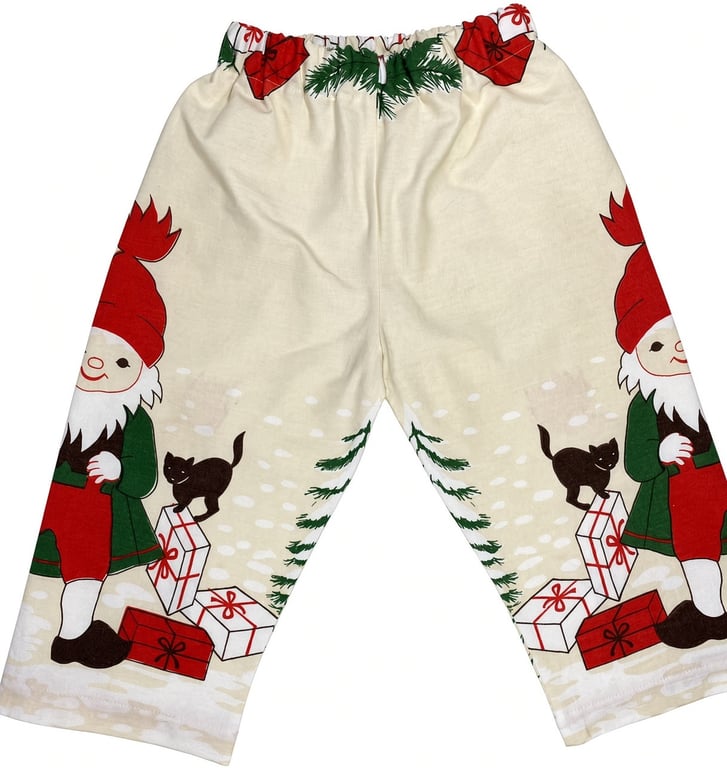 Børnebukser med julemotiv, der forestiller nisser med røde huer, sorte katte og julegaver på en beige baggrund.