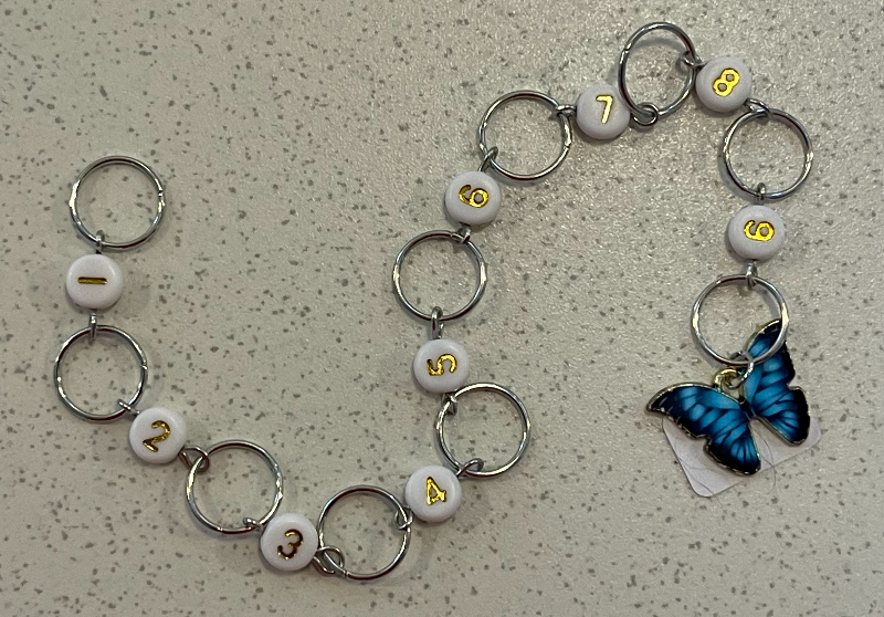 En række nøgleringe forbundet i nummerorden fra 1 til 9, hvor nummer 9 har en blå sommerfugl-vedhæng.