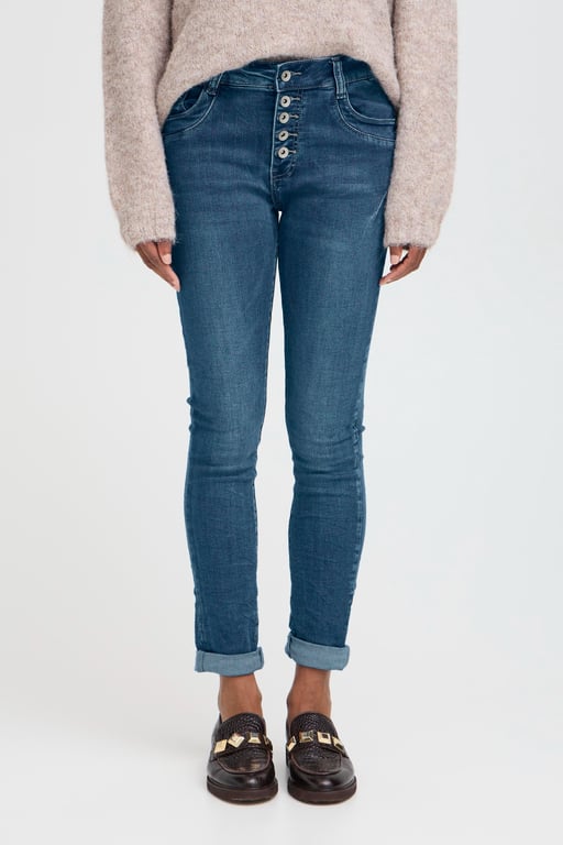 Tætsiddende blå jeans med synlige knapper foran, opsmøgede ben, beige striktrøje og sorte loafers med gulddetaljer.