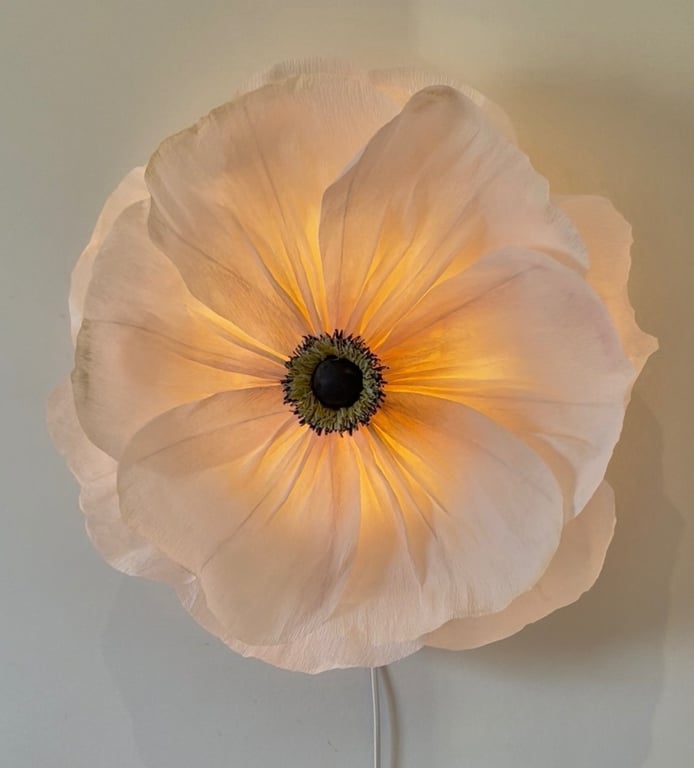 Stor blomst formet lampe med bløde, hvide kronblade der lyser varmt indefra.
