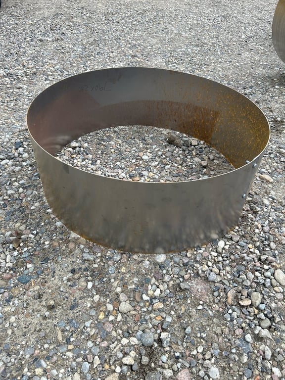 Rustet metalring placeret på grusbelagt jord.