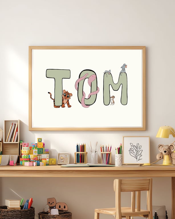 Illustration af navnet "TOM" i store grønne bogstaver med en tigerunge, en slange, en mus og to mus som dekoration, ophængt over et børnebord med farverige byggeklodser, farvekridt og legetøj.