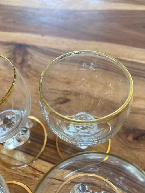 Nærbillede af tre små glas med guldkant placeret på et træbord. (4)