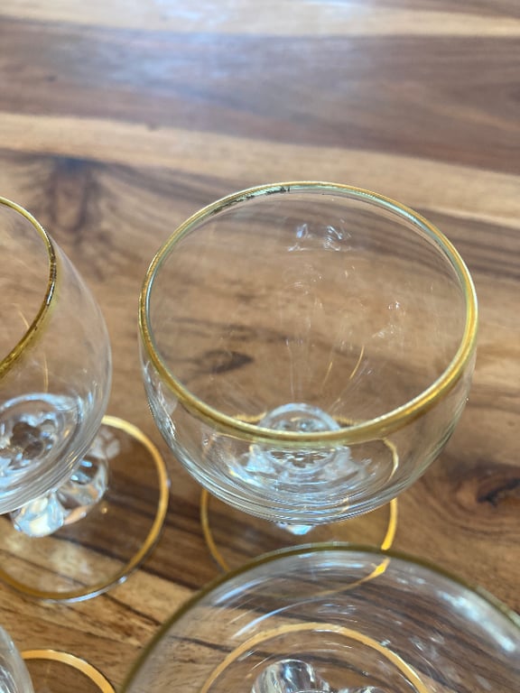 Nærbillede af tre små glas med guldkant placeret på et træbord. (4)