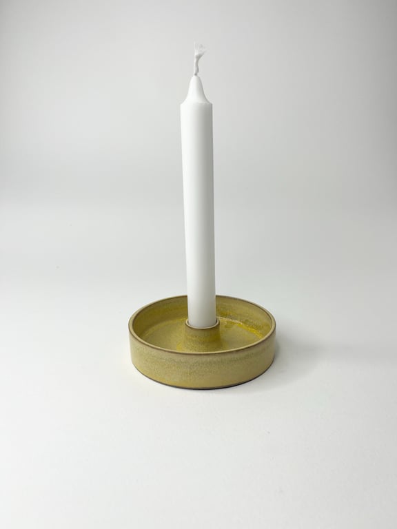 Hvid kronelys i grønlig keramiklysestage på hvid baggrund.