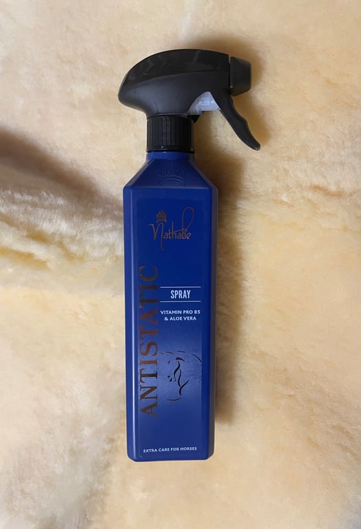 Blå sprayflaske med sort forstøverspray, mærket "Matthalie Antistatic Spray" med vitamin Pro B5 og aloe vera, til ekstra pleje af heste, placeret på en lys pelsagtig baggrund.