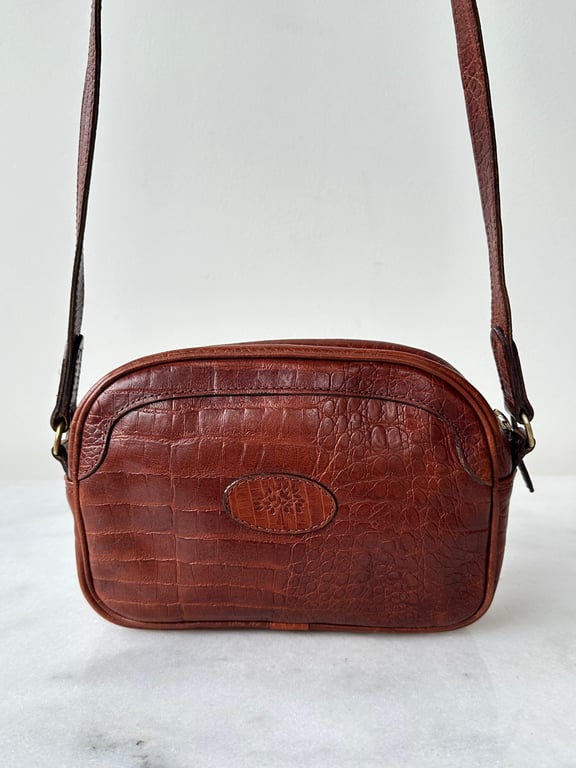 Brun lille skuldertaske i læder med krokodillemønster og justerbar rem.
