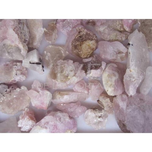 Billede af flere rå rosa og lilla krystaller og mineraler på en hvid overflade. (4)
