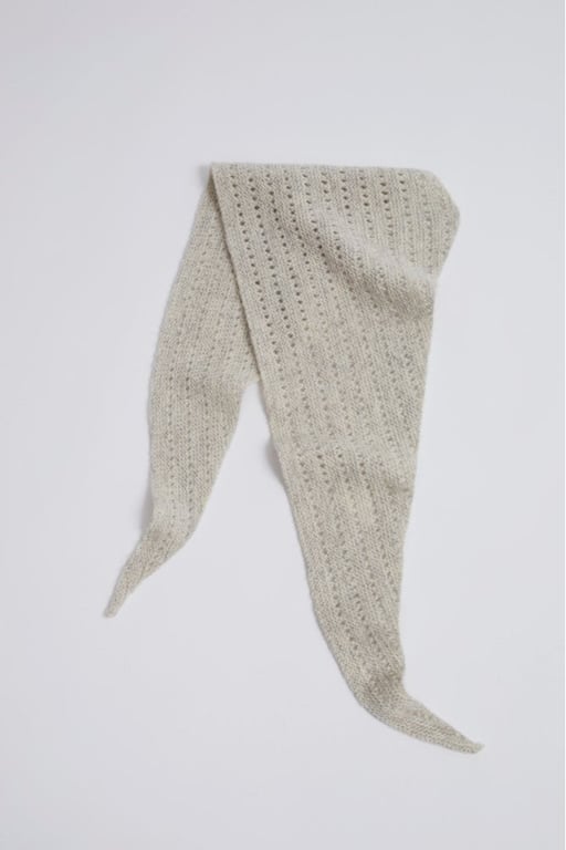 Beige strikket tørklæde med hulmønster, lagt ud fladt mod hvid baggrund.