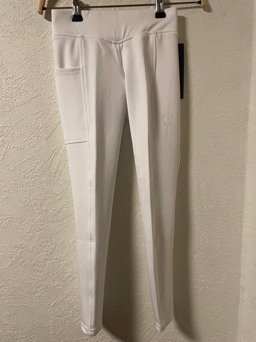 Hvide, tætsiddende leggings med sidelomme, hængende på en bøjle foran en væg. (1)