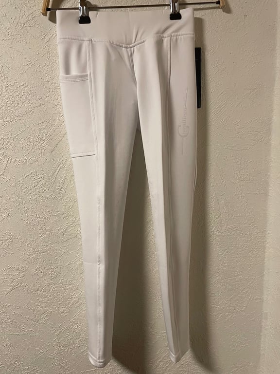Hvide, tætsiddende leggings med sidelomme, hængende på en bøjle foran en væg.