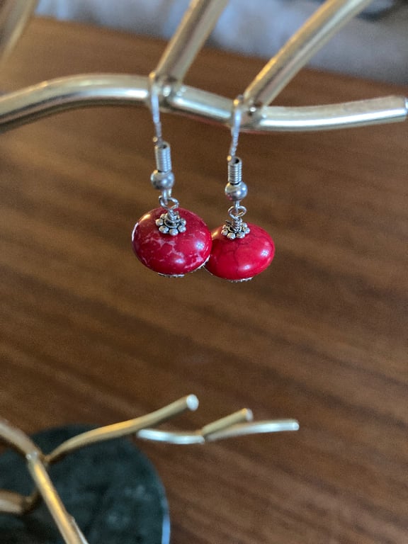 Næbøreringe med rød, rund sten og sølvdetaljer hængende på en metalsmykkestativ. (2)