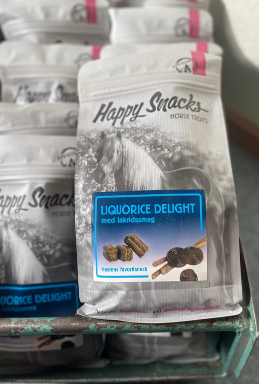 Pose med Happy Snacks hestegodbidder med lakridssmag, mærket "Liquorice Delight", vist på en butikshylde.