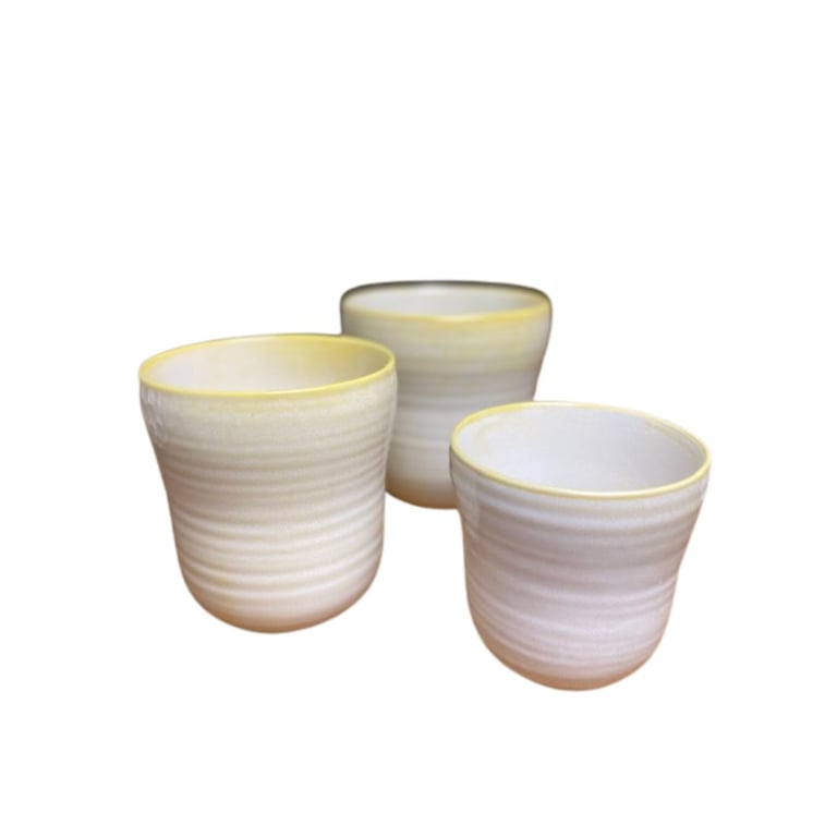 Tre keramikkrus med sandfarvet glaseret overflade og gul kant, placeret på hvid baggrund.