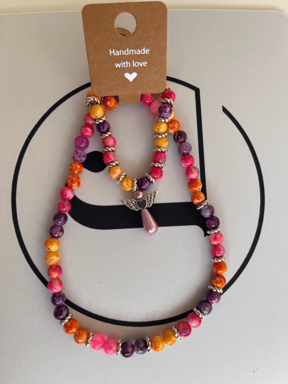 Colourfull, armbånd og halskæde, sæt. Perler i acryl og forsølvede mellem stykker, farver er mange, der er en engel i armbåndet.