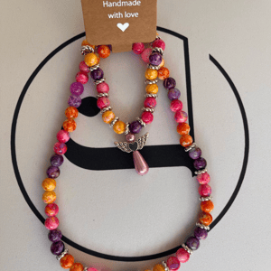Colourfull, armbånd og halskæde, sæt. Perler i acryl og forsølvede mellem stykker, farver er mange, der er en engel i armbåndet. – produktbillede