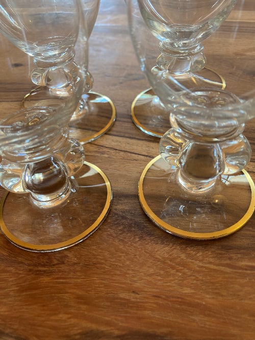 Fire gennemsigtige glas med guldkanter samlet på et træbord. (5)