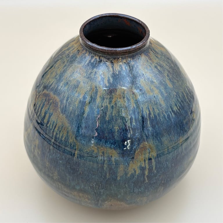 Blå og gul glasurdekoreret keramikvase med rund form og small åbning øverst.