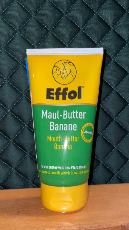 Tube med Effol Maul-Butter Banane mundsmør til heste, placeret foran en quiltet sort baggrund.