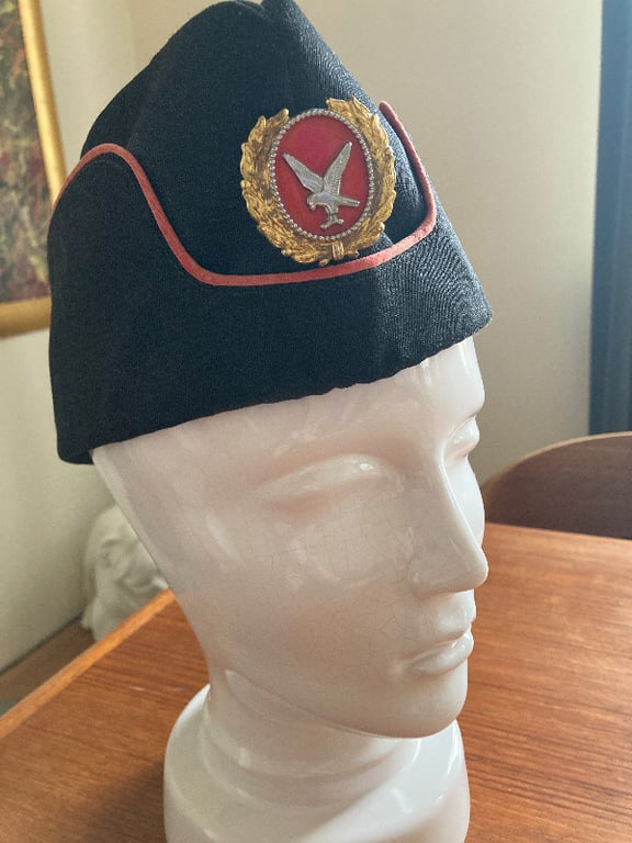Sort militær kasket med rød kant og emblem med fugl, placeret på en hvid mannequin-hoved. (2)