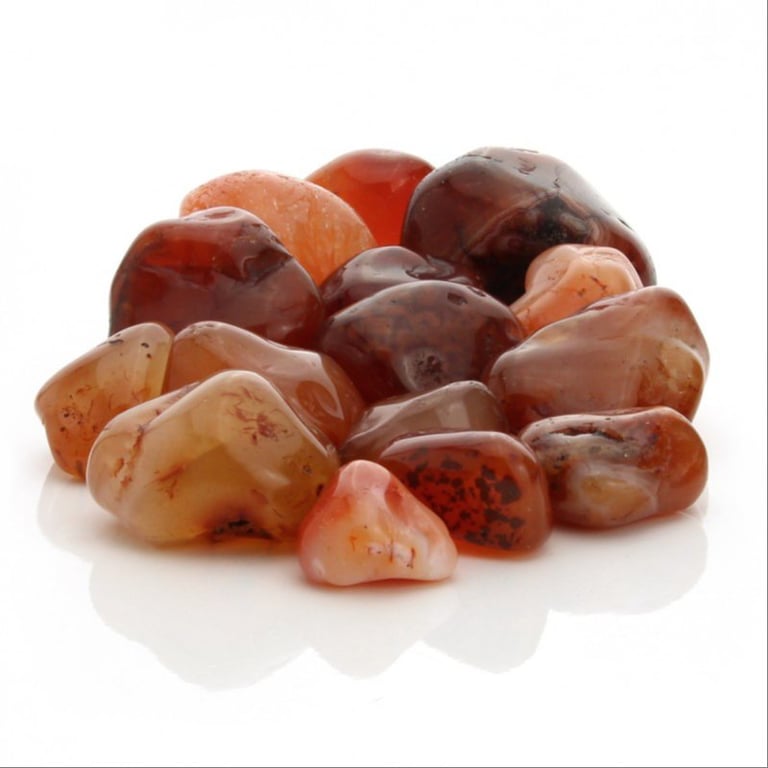 En gruppe polerede, røde og orange agatsten lagt sammen på en hvid overflade. (2)
