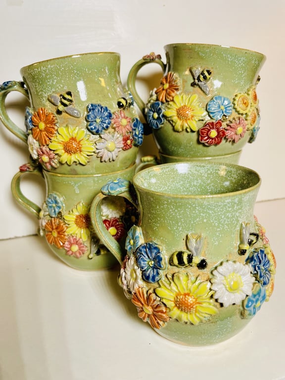 Fire grønne krus med relief af farverige blomster og bier.