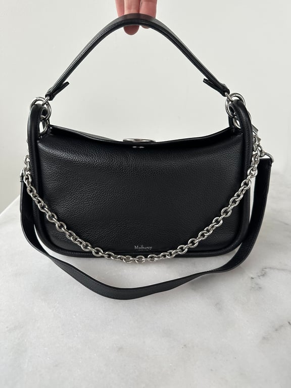 Sort Mulberry skuldertaske i læder med sølvfarvet kæde- og læderrem, holdt op i håndtag.