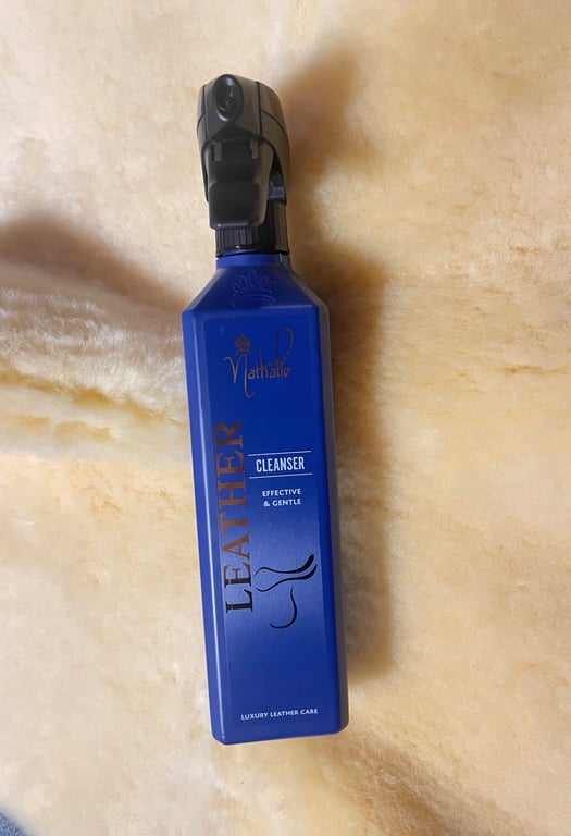 Flaske med blå læderrensningsspray på lysebrunt, blødt underlag.