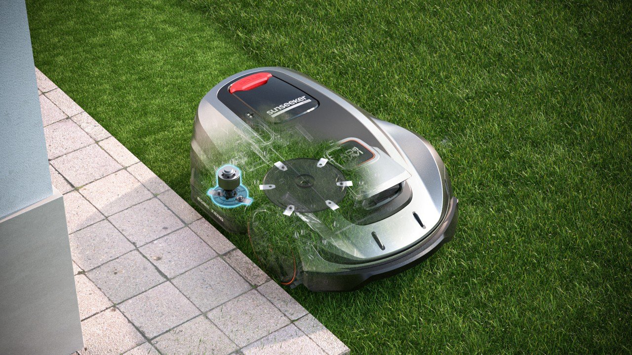 Robotplæneklipper på græs med delvist gennemsigtig overflade, der viser dens indre mekanisme.