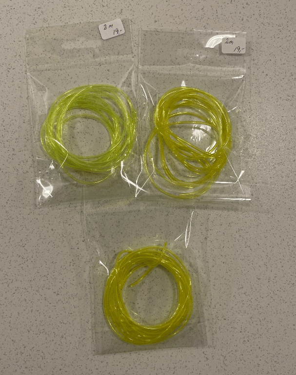 Tre små plastikposer med sammenrullede, gule plastikrør, hver pose mærket med "2 m" og "19,-".