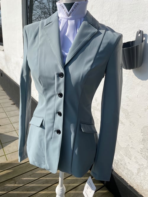 Gråblå dameskræddersyet blazer med fire knapper og to lommer, vist på en mannequin uden hoved, placeret udenfor mod en hvid væg. (1)