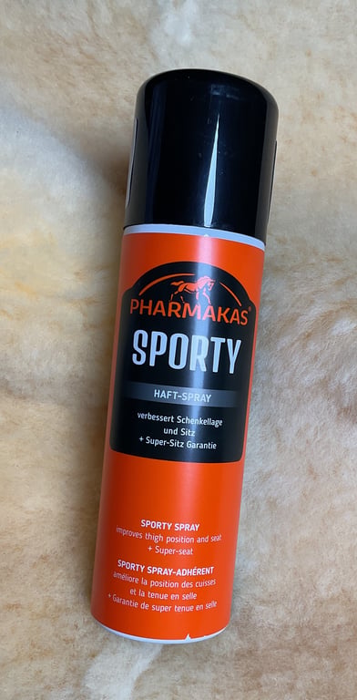 Spraydåse med mærket Pharmaka's Sporty, designet til forbedring af lårposition og sadeltilpasning, står på et lyst, blødt underlag.