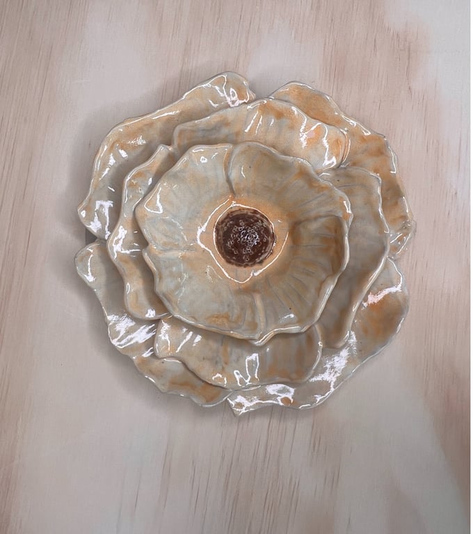 Glaseret keramisk blomst i beige og brune nuancer placeret på lyst træbord.