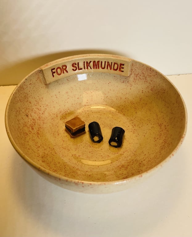Skål med skriften "FOR SLIK MUNDE" indeholdende karameller og lakridsstykker.