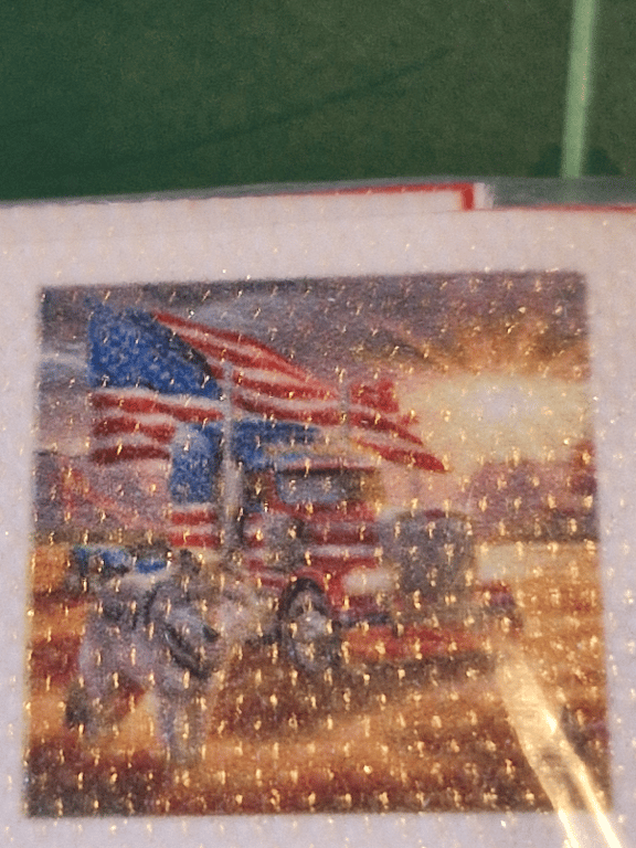 Billede af en lastbil malet i amerikanske flagfarver med flere amerikanske flag og en hest foran, med en solnedgang i baggrunden.