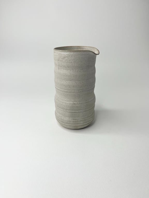 Grå keramikkande med ribbet tekstur og en lille tud, placeret på hvid baggrund.