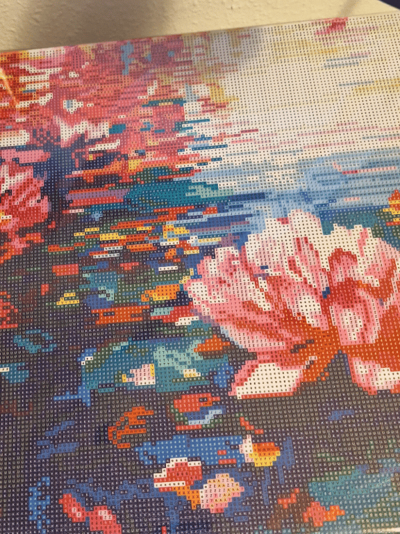 Close-up af farverigt diamantmaleri med blomstermotiv og nuancer af pink, blå, orange og grøn.