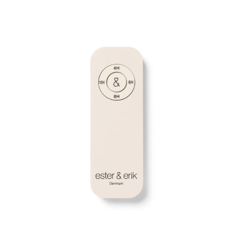 Fjernbetjening i beige med cirkulært ur og tidspunkter 4H, 6H, 8H, 10H samt teksten "ester & erik Denmark" nederst.