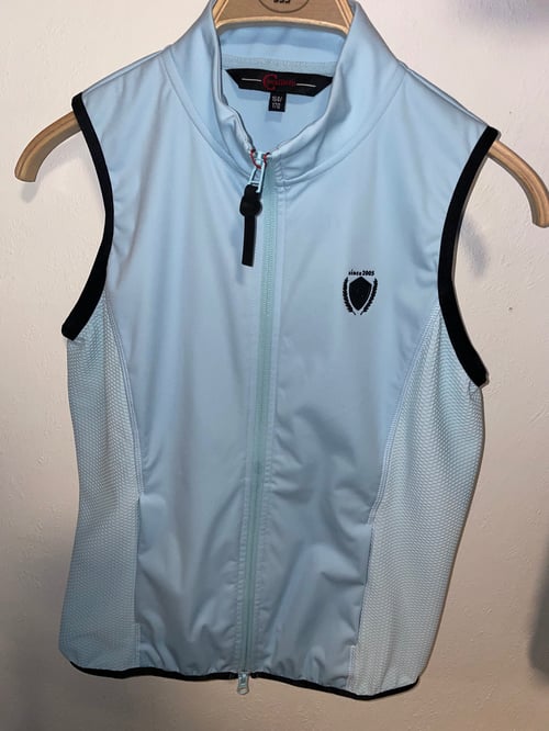 Lys blå, ærmeløs sportsvest med sort kant langs ærmegab, lynlås foran og lille logo på brystet. (1)