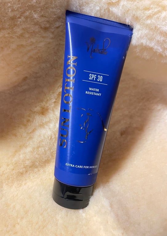 Blå tube med solcreme til heste, SPF 30, vandafvisende, på cremefarvet blødt underlag.