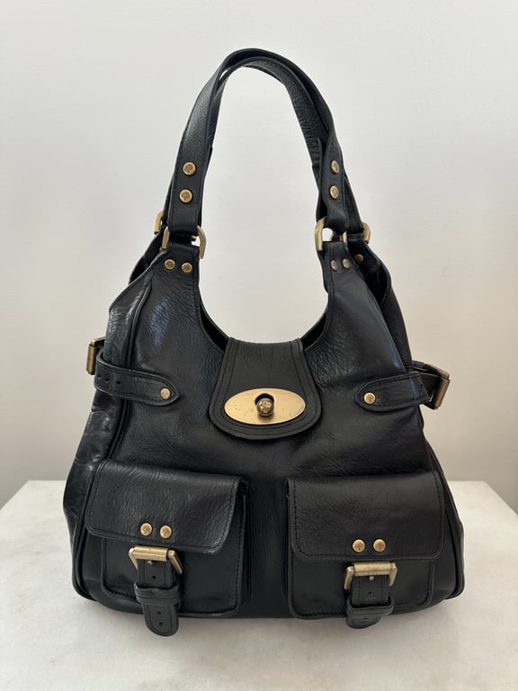 Sort skuldertaske i læder med to frontlommer og gyldne metalspænder og nitter.