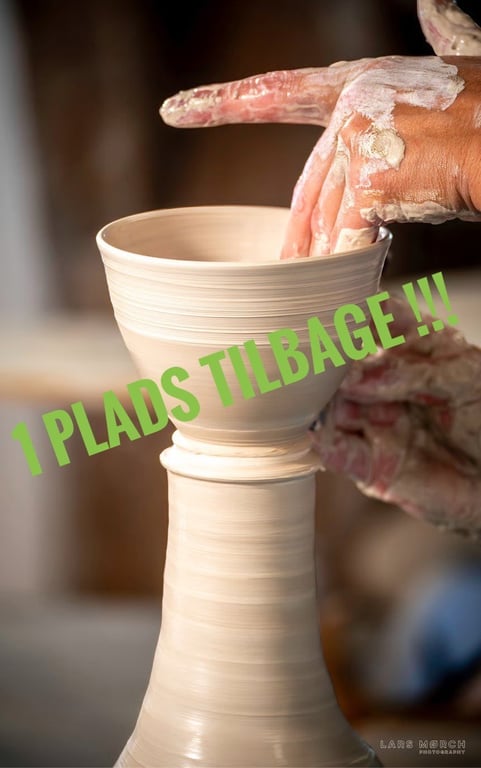 Hænder med ler, der former en kop på en drejeskive med teksten "1 PLADS TILBAGE !!!" over billedet.